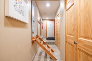 A hallway with wooden doors, a framed floral artwork, and a wooden ladder. - BBQ | Private garage | Walk to Golfing & Lost Lake (Whistler)
