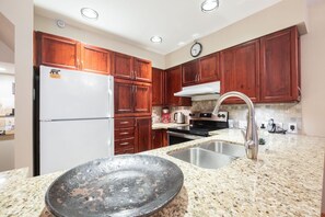 A kitchen with wooden cabinets, a stainless steel sink, a stove, and a refrigerator. - BBQ | Private garage | Walk to Golfing & Lost Lake (Whistler)