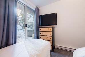 Ein Hotelzimmer mit einem Bett, einem Schminktisch, einem Fernseher und einer Glasfranzösisch, die zu einem verschneiten Außenbereich führt.
