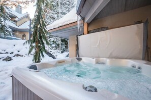 A hot tub in a snowy outdoor setting with a view of a house and stairs. - Gorgeous townhouse | Private hot tub | BBQ (Whistler)