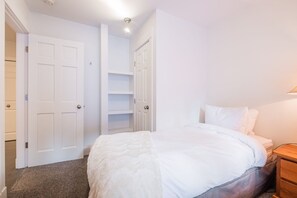 A bedroom with a bed, a nightstand, a wardrobe, and a built-in shelving unit. - Gorgeous townhouse | Private hot tub | BBQ (Whistler)