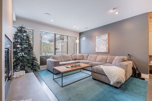 Ein modernes Wohnzimmer mit einem Ecksofa, einem Couchtisch, einem Weihnachtsbaum und einer Gitarre.