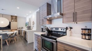 A modern kitchen with a central island, stainless steel appliances, and wooden cabinetry. - Gorgeous townhouse | Private hot tub | BBQ (Whistler)