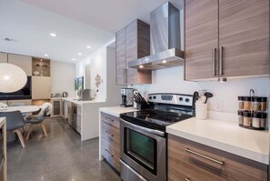 A modern kitchen with a central island, stainless steel appliances, and wooden cabinetry. - Gorgeous townhouse | Private hot tub | BBQ (Whistler)