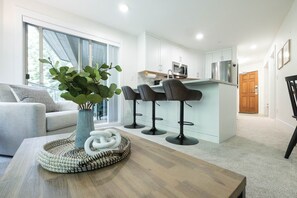 Eine moderne Küche mit weißen Schränken, einem Edelstahl-Kühlschrank und einer Bar mit zwei Hockern.