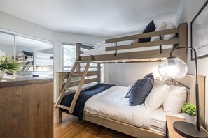 A bunk bed with a ladder, a bedside table with a lamp, and a potted plant. - AC in bedrooms | Private hot tub | Pets | Location (Whistler)