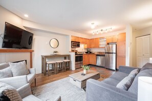 A modern living room with a sofa, a coffee table, and a TV mounted on the wall. - AC in bedrooms | Private hot tub | Pets | Location (Whistler)