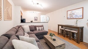 Un salon moderne avec un canapé d’angle, une table basse en bois et un coin repas agrémenté d’une banquette.