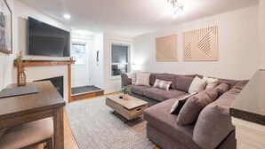 Un salon moderne avec un canapé, une table basse, un téléviseur et une cheminée.