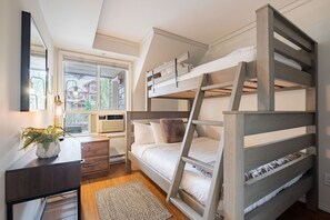 Ein Schlafraum mit Etagenbetten, einem Schreibtisch und einem Fenster.