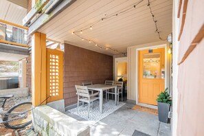 A covered outdoor seating area with a table and chairs, a door with a number, and a bike parked outside. - Beautiful 2BDR townhouse | Private hot tub | Pets (Whistler)