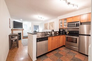 A modern kitchen with stainless steel appliances, wooden cabinets, and a tiled backsplash. - Beautiful 2BDR townhouse | Private hot tub | Pets (Whistler)