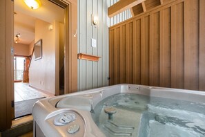 Ein Whirlpool in einem Raum mit Holzwänden, einem Spiegel und einer Leuchte.