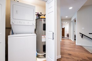 A laundry room with a washer and dryer, a stainless steel refrigerator, and a wooden floor. - Large deck | Private Hot Tub | BBQ | Pet friendly (Whistler)