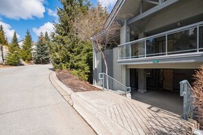 A building with a covered entrance, a clear sky, and trees in the background. - Large deck | Private Hot Tub | BBQ | Pet friendly (Whistler)