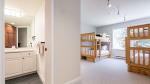 Un dormitorio con literas, una ventana y un baño con espejo y armarios.