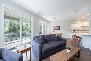 Un salon moderne avec un canapé gris, une table basse en bois et un coin repas comprenant une table et des chaises en bois.