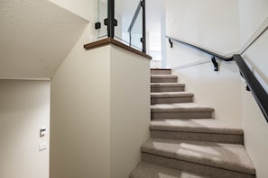 A carpeted staircase with a glass railing and a wooden handrail. - Large deck | Private Hot Tub | BBQ | Pet friendly (Whistler)