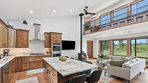 Une cuisine spacieuse avec des meubles en bois, un grand îlot central et un coin repas comprenant un canapé et des chaises.