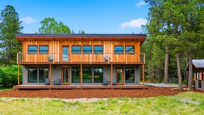 Une cabane en bois à deux étages, dotée d’un balcon, de grandes fenêtres et d’une terrasse.