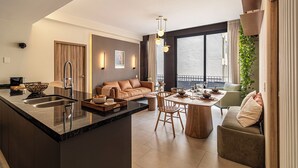 A modern kitchen with a central island, a dining area with a wooden table and chairs, a sofa, and a large window with curtains. - San Luis by Kukun Apartments (Ciudad de México)