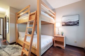 A bunk bed room with a ladder, bedside table, lamp, and a painting on the wall. - Large patio | BBQ | Hot tub | Free parking (Whistler)