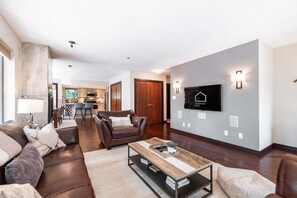Ein modernes Wohnzimmer mit einer Ledersofa, einem Couchtisch und einem an der Wand befestigten Fernseher.