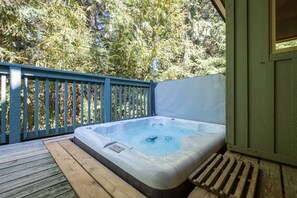 A hot tub on a wooden deck with a blue railing, surrounded by trees. - Close to Blackcomb skiing | Private hot tub | BBQ (Whistler)