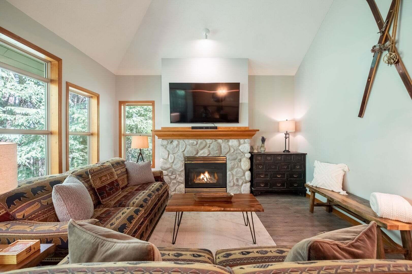 Ein gemütliches Wohnzimmer mit Kamin aus Stein, einem großen Flachbildfernseher und einer bequemen Couch.