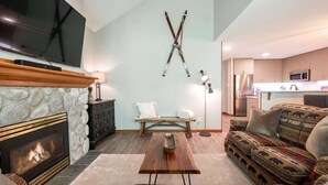 Un salon avec une cheminée, un téléviseur, un canapé et un tapis à motifs.