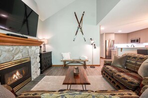 A living room with a fireplace, a television, a sofa, and a patterned rug. - Close to Blackcomb skiing | Private hot tub | BBQ (Whistler)