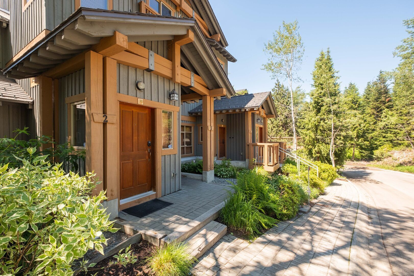 A wooden house with a front porch, a door, and a small garden area.