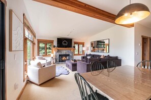 A modern living room with a fireplace, a dining area with a wooden table, and a large mirror. - Pets | BBQ | Sundeck | Private garage | Ski-in/out (Whistler)