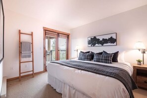 A bedroom with a bed, a ladder, a window, and a nightstand with a lamp. - Pets | BBQ | Sundeck | Private garage | Ski-in/out (Whistler)