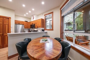 A modern kitchen with wooden cabinets, stainless steel appliances, and a round dining table with chairs. - Pets | BBQ | AC in bedrooms | Superb location (Whistler)