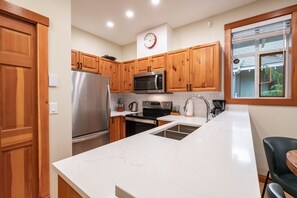 Uma cozinha moderna com armários de madeira, eletrodomésticos de aço inoxidável e bancada de mármore branco.