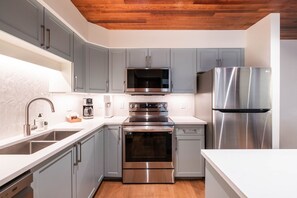 A modern kitchen with grey cabinets, stainless steel appliances, a built-in oven, and a dishwasher. - Pet friendly | Renovated | Free parking | Spacious (Whistler)