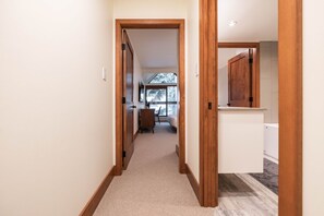 A hallway with a carpeted floor, wooden door frames, and a view into a room with a bed and a window. - Pet friendly | Renovated | Free parking | Spacious (Whistler)