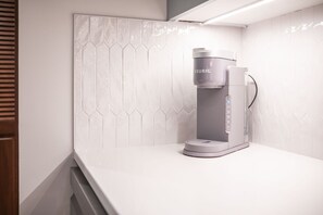 A modern coffee machine on a white countertop with a geometric tile backsplash. - Pet friendly | Renovated | Free parking | Spacious (Whistler)