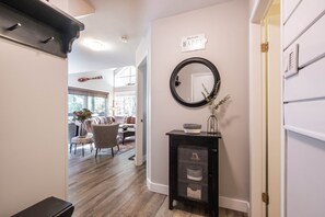 A hallway with a black console table, a round mirror, and a sign on the wall. - Walk to Creekside Gondola | BBQ | Pets | Free parking (Whistler)