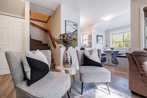 A modern living room with a staircase, a dining area, and a kitchen. - Walk to Creekside Gondola | BBQ | Pets | Free parking (Whistler)