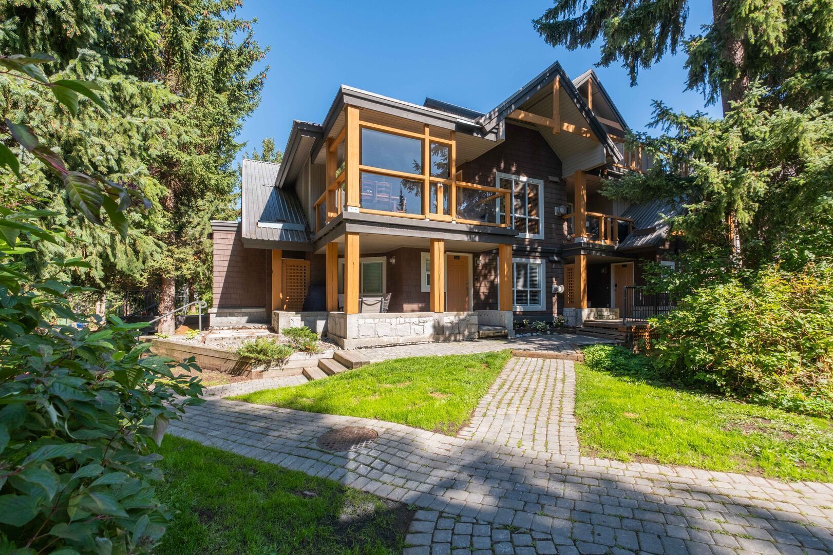 A two-story house with a stone foundation, large windows, and a covered porch.