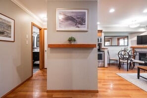A hallway leading to a kitchen with a dining area, wooden flooring, and a framed picture on the wall. - Great location | Hot tub, pool & sauna | BBQ | AC (Whistler)