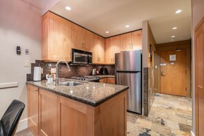 A kitchen with granite countertops, stainless steel appliances, wooden cabinets, and a stone tile backsplash. - Free Parking | Steps to Blackcomb | Shared Hot Tub (Whistler)