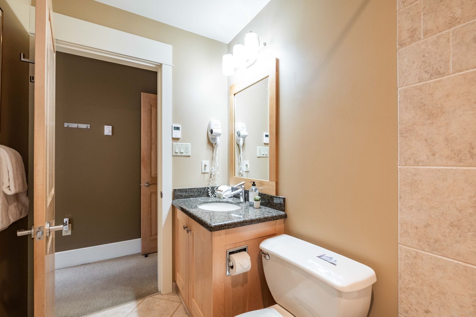 A bathroom with a sink, toilet, and a mirror.