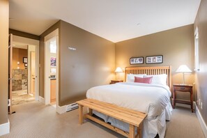 A hotel room with a bed, bedside tables, a bench, and a bathroom visible through an open door. - Free Parking | Steps to Blackcomb | Shared Hot Tub (Whistler)