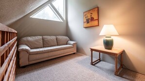 Um quarto aconchegante com um sofá, uma luminária e um quadro na parede.