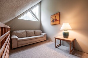 Ein gemütliches Zimmer mit einer Couch, einer Lampe und einem Bild an der Wand.