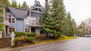 A two-story house with a balcony, a driveway, and a street view. - Pet friendly | Hot tub | BBQ | Free parking (Whistler)