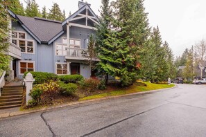 A two-story house with a balcony, a driveway, and a street view. - Pet friendly | Hot tub | BBQ | Free parking (Whistler)